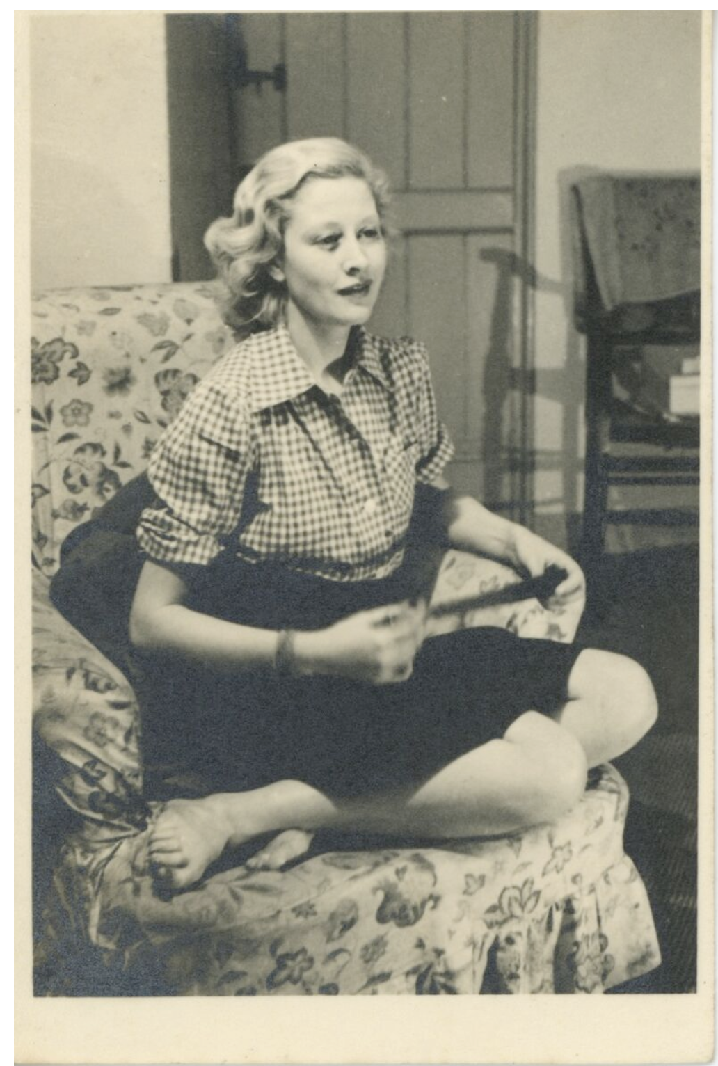 Black and white photograph of a young woman seated on a floral sofa.